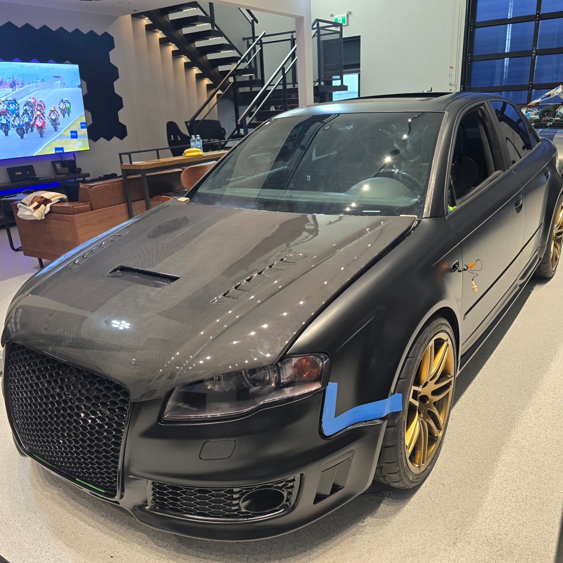 Matte black Audi RS4 with carbon hood and gold wheels in the Heckya showroom